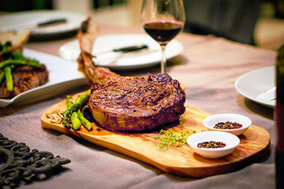 Succulenta bistecca su tagliere di legno accompagnata da vino rosso: un piacere culinario durante gli Steakdays di novembre alla Großberghütte nella Valle di Altafossa.