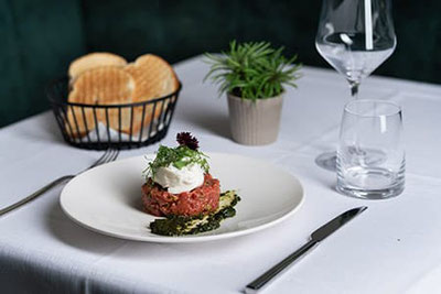 Genuss im Restaurant Ban Max in Truden: stilvoll gedeckter Tisch mit Pasta, Salat, Fleischgericht und Wein – italienische Küche in Südtirol.