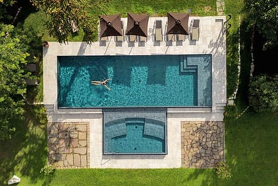 Luftaufnahme des Außenpools im Hotel Castel Rundegg in Meran, mit Sonnenliegen und Schirmen im großzügigen Hotelgarten – perfekter Ort für totale Entschleunigung.