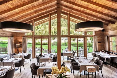 Eggile Restaurant in Vals: stilvoll gedeckter Gastraum mit großen Fenstern, Blick auf das Valler Tal in Südtirol, gemütlich-moderne Atmosphäre mit Alpenflair.