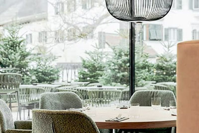 Modernes, geschwungenes Gebäude des Soley Restaurants in Brixen mit Terrasse und Olivenbaum – elegantes Design trifft mediterranes Flair im Herzen Südtirols.