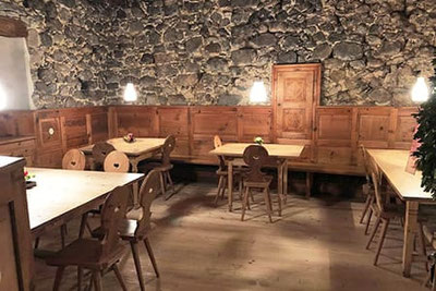 Gemütliche Stube im Buschenschank Wassererhof bei Völs am Schlern mit Holzmöbeln, Steinmauern und stimmungsvoller Beleuchtung – Südtiroler Tradition erleben.