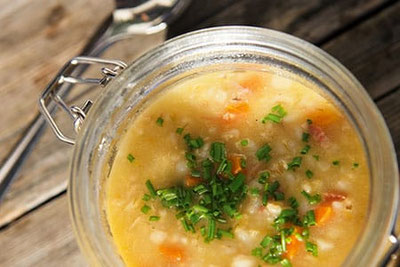Herzhafte Gerstsuppe im Glas, garniert mit frischem Schnittlauch – traditionelles Südtiroler Gericht, serviert auf rustikalem Holztisch im Hinterpasseier.