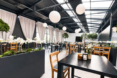 Bistro Orchidea Gargazzone: locale luminoso con orchidee, tavoli moderni e un'ampia vetrata, atmosfera elegante nel mondo delle orchidee di Raffeiner