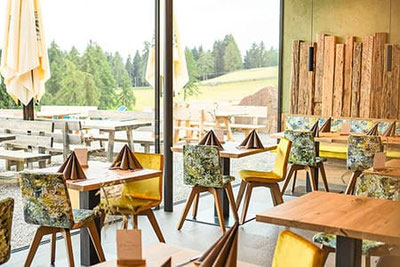 Arredamento moderno e accogliente al ristorante di montagna Lanzenschuster a San Genesio, con vista sulle distese del Monzoccolo e calde tonalità naturali del legno.