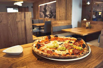 Pizza appena sfornata con salame e peperoni nella pizzeria Luisl’s Keller a Merano, Alto Adige