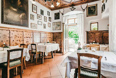 Historisches Stüberl im Restaurant Finsterwirt in Brixen mit holzgetäfelten Wänden, antiken Bildern und liebevoll gedeckten Tischen – traditionelles Südtiroler Ambiente.