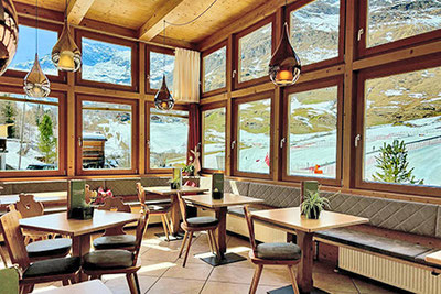 Giardino d'inverno nel ristorante Rosmarie a Plan, Alto Adige - atmosfera accogliente con vista panoramica sul paesaggio montano innevato della Val Passiria.