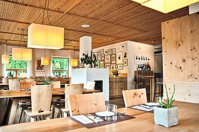 Sala moderna del ristorante Binderstube a Fiè allo Sciliar con arredi in legno, luce calda, tavoli apparecchiati e atmosfera accogliente ed elegante.