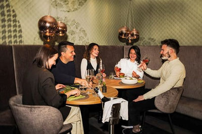 Freunde genießen Aperitif und mediterrane Gerichte im Café Bistro Emmi in Schenna bei Meran in stilvollem Ambiente in Südtirol.