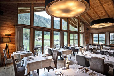 Eggile Restaurant in Valles: stilvoll gedeckter Gastraum mit großen Fenstern, Blick auf das Valler Tal in Südtirol, gemütlich-moderne Atmosphäre mit Alpenflair.