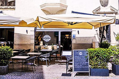 Außenansicht des Restaurants Argentieri in der Bozner Altstadt mit stilvoll gedeckter Terrasse, Sonnenschirmen und Menütafel auf Kopfsteinpflaster.