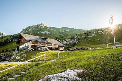 La Malga Gampen a Funes all'alba, circondata da prati verdi e montagne: meta escursionistica molto apprezzata con rifugio e vista sulle Dolomiti.
