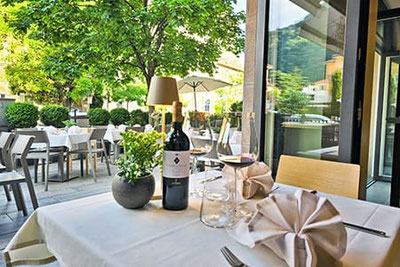 Elegant gedeckter Tisch mit Rotwein, Gläsern und Deko auf der Terrasse des Weinbistro Gries 13 in Bozen – stilvolles Ambiente unter Bäumen am Grieser Platz.