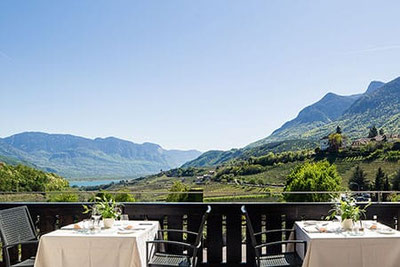 Vista panoramica sui vigneti, sulle montagne e sul Lago di Caldaro dalla terrazza del ristorante Ritterhof a Caldaro: il luogo perfetto per un pasto delizioso in Alto Adige.