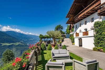 Accogliente giardino con posti a sedere e vista panoramica sulla Valle dell'Adige presso la locanda Oberlechner a Velloi, sopra Lagundo, in Alto Adige.