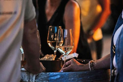 Aperitivo Lungo am Vigiljoch bei Stube Ida: Gäste genießen Wein und Snacks in entspannter Sommeratmosphäre.