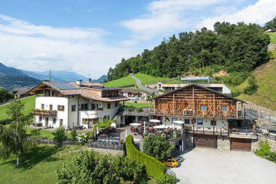 Pitschlmann Restaurant, Pizzeria & Buschenschank in Völs am Schlern – sonnige Panoramalage mit Terrasse, umgeben von Wiesen und Bergen, ideal für Genießer.