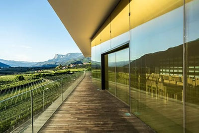 Cantina Merano: terrazza dell’enoteca panoramica con facciata in vetro, vista sui vigneti e sul territorio di Merano, design moderno e sale degustazione eleganti