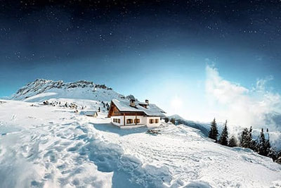 Verschneite Gampenalm im Villnösstal bei Nacht, unter klarem Sternenhimmel mit Blick auf die Dolomiten im Naturpark Puez-Geisler.