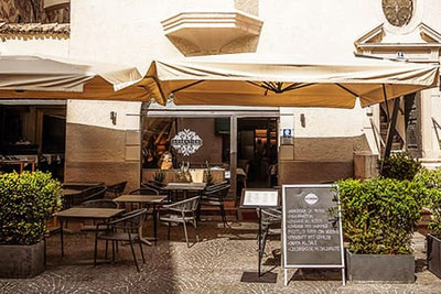 Area esterna del Ristorante Argentieri a Bolzano con ombrelloni, tavoli all’aperto e lavagna del menù davanti al ristorante di pesce nel centro storico.