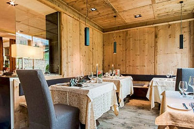 Elegantes Restaurant Kirchsteiger in Völlan mit warmem Holzinterieur, stilvoll gedeckten Tischen und gemütlicher Atmosphäre für feine Gourmetabende in Südtirol.