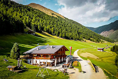 Die Großberghütte im sonnigen Altfasstal oberhalb von Meransen – umgeben von grünen Wiesen, Bergen und Wäldern, idealer Ort zum Wandern und Genießen in Südtirol.