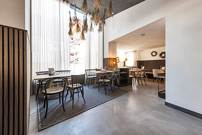 Das modern gestaltete Kobler Bistro & Café in St. Leonhard mit großen Fenstern, hellem Tageslicht, Naturmaterialien und stilvoller Einrichtung – ideal zum Frühstücken und Verweilen.