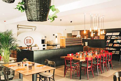 Moderner Gastraum der Pizzeria SEM in Töll bei Partschins mit großem Holzofen, warmem Licht und lockerer Bistro-Atmosphäre nahe Meran.