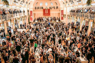 La grande sala del Kurhaus di Merano durante il Merano WineFestival con numerosi visitatori, tavoli di degustazione e un'atmosfera festosa: un evento all'insegna del piacere culinario in Alto Adige.