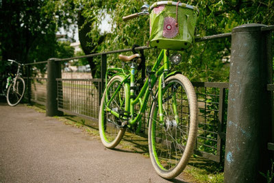 Ein grünes Fahrrad lehnt an einem rostigen Brückengeländer