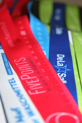 Es sind mehrere Lanyards in verschiedenen Farben sichtbar. Auf ihnen sind das Logo von Fivepoints sowie das der Dela Salle Schule zu erkennen.
