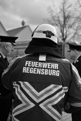 Mann in Einsatzkleidung der Feuerwehr mit Helm von hinten gesehen. "Feuerwehr Regensburg" ist zu lesen.