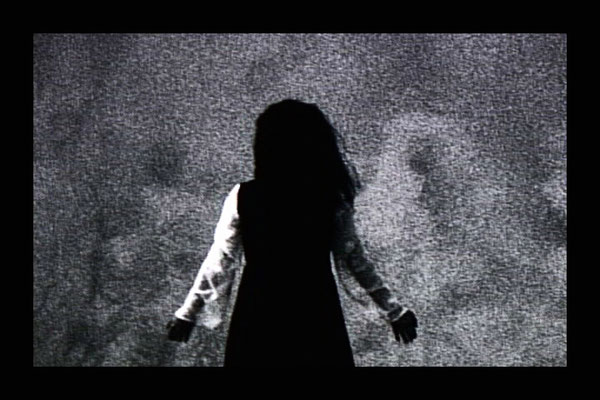 back view of dancer against wall of sand dune in the wind