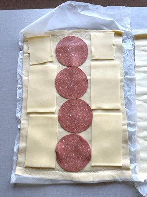 Auf den Pizzateig Käse und Schinken oder Salami o.ä. geben