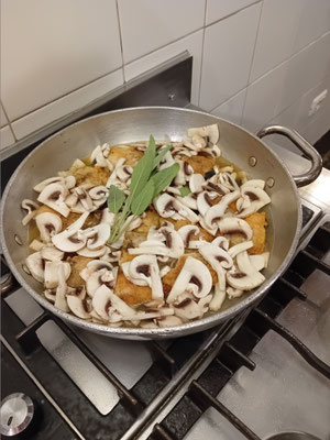 das Huhn mit Pilzen, Salbei und Weißwein brutzelt ...