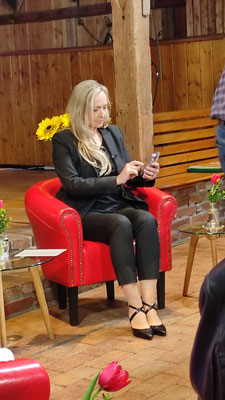 Susan Froitzheim auf dem roten Sofa, mit Handy