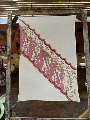 Colouring in batik wax outline on framed cotton cloth in pink
