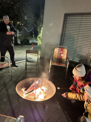 Children roasting marshmallows around a campfire during a Christmas celebration.