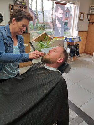 Barbier Ingrid verzorgd een baard