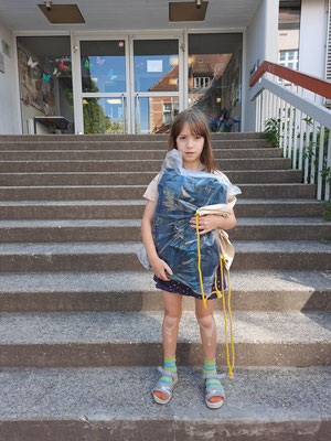 Eine Schülerin steht mit seinem Gewinn in der Hand auf den Treppen vor dem Schulgebäude.