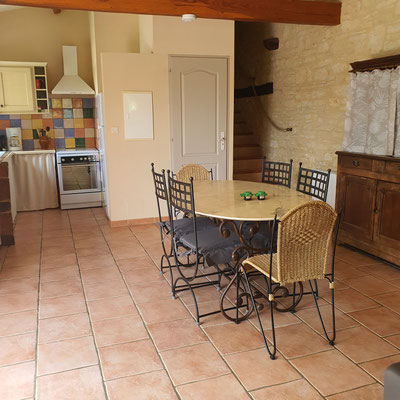 Notre gîte, coin salle à manger avec une table de 6 personnes et 6 chaises et un vaisselier et un petit cadeau de bienvenue vous attend sur la table