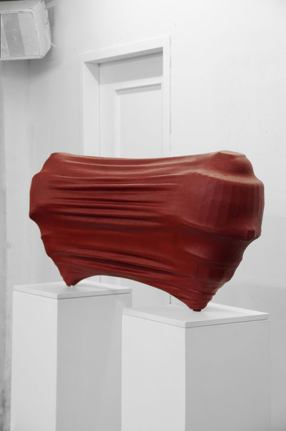 Skulptur von Andreas Jonak. Zwei sich voneinander abstoßende Körper, die von eine gespannten roten Membran umhüllt sind. 