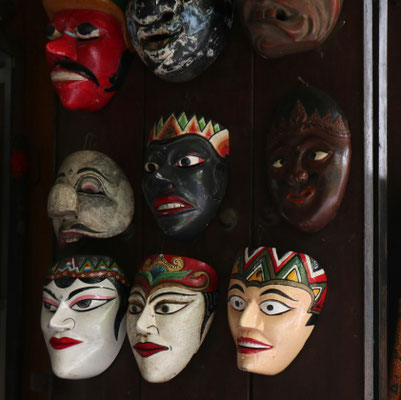 Unterschiedliche, geschnitzte Masken an einer Wand.