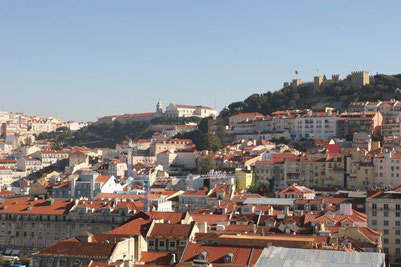 Massive Burgmauern von Sao Jorge auf einem grünen Hügel in Lissabon, die Stadt darunter ©My own Travel Städtereise Lebendiges Lissabon