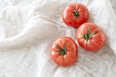 真っ赤なトマトが3つ、リネンストールのうえに並んでいる。