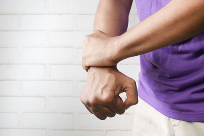 Mann greift mit seiner linken Hand um sein rechtes Handgelenk
