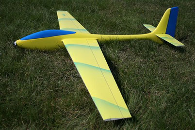 planeur Voltij Aeromod jaune et bleu primaire, posé dans l'herbe