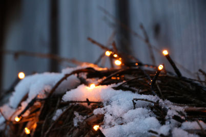 Kranz aus Zweigen mit Lichterkette und Schnee