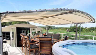 Deck der Hotelbarge Enchanté mit überdachtem Esstisch und Whirlpool
